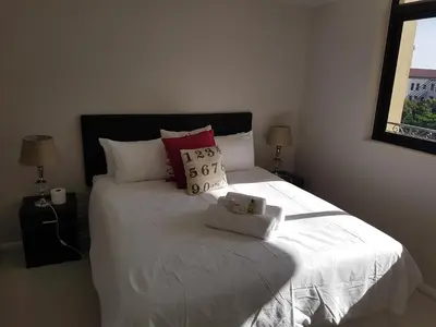 a bedroom with a bed with white sheets and pillows at The Island Club Apartment in Cape Town