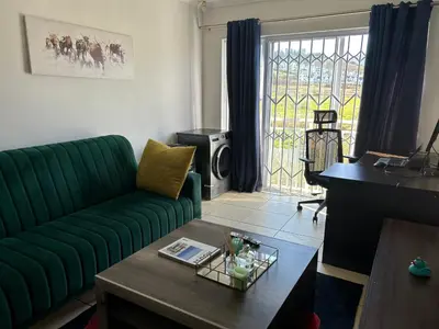 a living room with a green couch and a table at 2 Bedroom Shared kitchenette Apartment with beautiful views in Stellenbosch