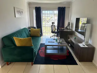 a living room with a green couch and a tv at 2 Bedroom Shared kitchenette Apartment with beautiful views in Stellenbosch
