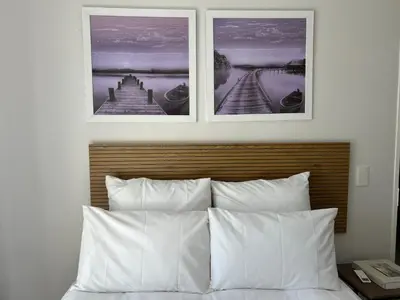 two pictures hanging above a bed with white pillows at 2 Bedroom Shared kitchenette Apartment with beautiful views in Stellenbosch