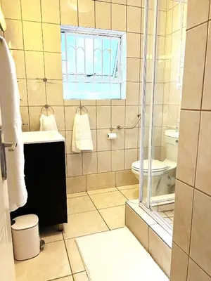 a bathroom with a toilet and a glass shower at Panthera Cottage Milnerton in Cape Town