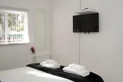 a room with a bed with a tv on the wall at Panthera Cottage Milnerton in Cape Town