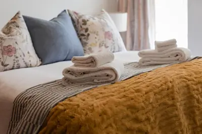 a bed with towels stacked on top of it at Silvertree Collective Central Family Home in Stellenbosch