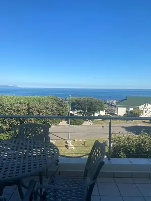a patio with a table and chairs and the ocean at 42 Whale Rock Estate in Hermanus