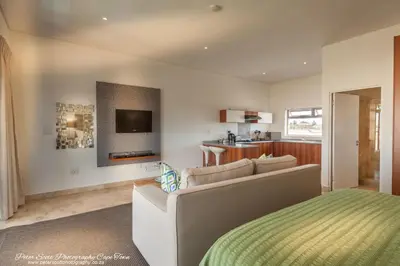 a living room with a couch and a television at Sunset Beach Luxury Apartments in Cape Town