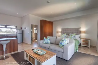 a living room with a couch and a bed at Sunset Beach Luxury Apartments in Cape Town