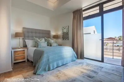 a bedroom with a bed and a large window at Sunset Beach Luxury Apartments in Cape Town