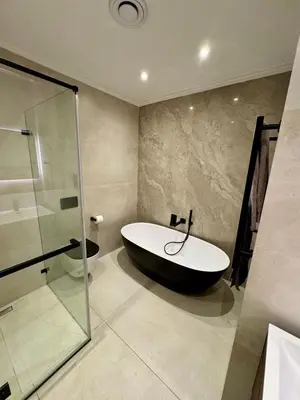 a bathroom with a bath tub and a glass shower at 4-Bedroom cabana at Dolphin Beach in Cape Town