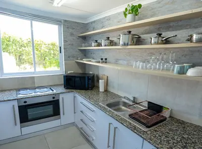 a kitchen with white cabinets and a sink and a window at The One on Pienaar in Cape Town
