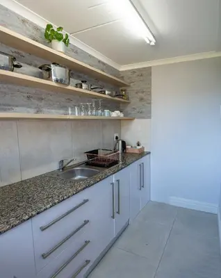 a kitchen with white cabinets and a sink at The One on Pienaar in Cape Town