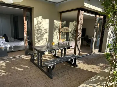 a picnic table with a bench on a patio at Luxury Vineyard Apartment in Cape Town