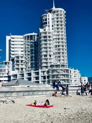 a group of people on a beach with tall buildings at Hibernian 10.02 in Cape Town