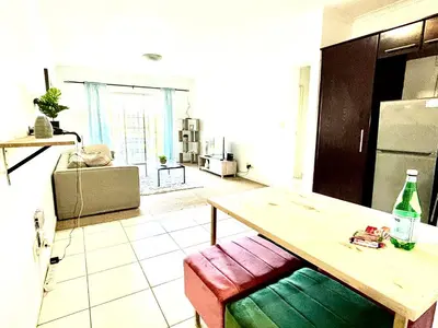 a living room with a table and a kitchen at Cozy&warm apartment in Century city in Cape Town