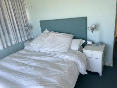 a white bed with a blue headboard and a night stand at Oceans Edge - Hermanus Beach Club in Hermanus