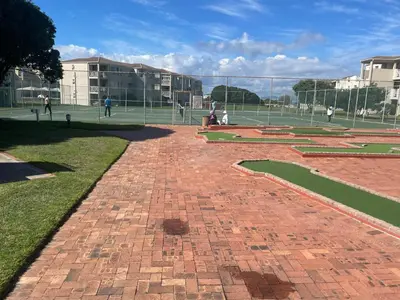 a brick walkway with people playing tennis on a court at Oceans Edge - Hermanus Beach Club in Hermanus