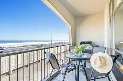 a balcony with a table and chairs and a view of the beach at Witsand 102 in Bloubergstrand