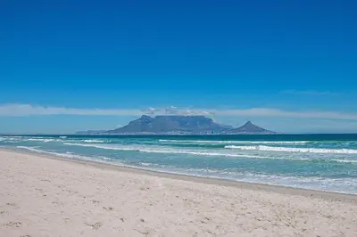 an empty beach with a mountain in the background at Witsand 102 in Bloubergstrand