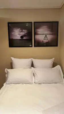 a white bed with three pictures on the wall at Studio Apartment Paarl Central in Paarl
