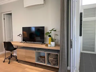 a room with a desk with a television and a chair at The Oak Suite - 7 on Murray Historic Stellenbosch in Stellenbosch