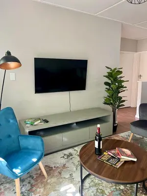 a living room with a television on a wall with a table at Akker in Stellenbosch