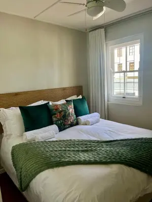 a bedroom with a large bed with green and white pillows at Akker in Stellenbosch