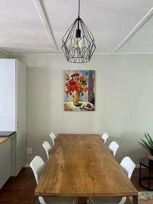 a dining room with a wooden table and a painting at Akker in Stellenbosch