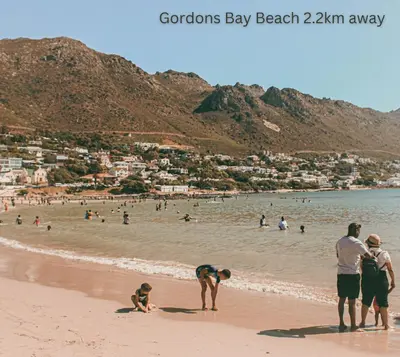 a group of people standing on a beach at Modern 2 bedroom apartment close to shops & beach in Gordonʼs Bay