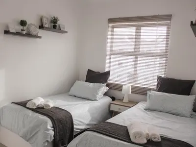 two twin beds in a room with a window at Modern 2 bedroom apartment close to shops & beach in Gordonʼs Bay