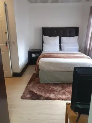 a bedroom with a large bed with a black headboard at Ludinz Guest House, Self catering in Cape Town