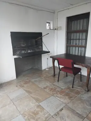 a room with a table and a chair and a piano at Ludinz Guest House, Self catering in Cape Town