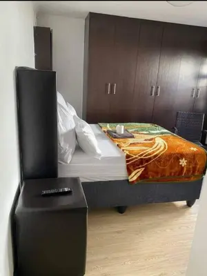 a bedroom with a bed with a chair next to it at Ludinz Guest House, Self catering in Cape Town