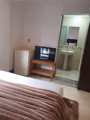 a bedroom with a television and a bathroom with a sink at Ludinz Guest House, Self catering in Cape Town