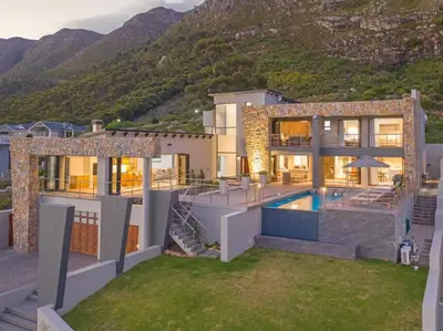 a house with a swimming pool in front of a mountain at Waterstone Villa in Hermanus