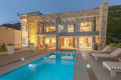 a large house with a swimming pool in front of it at Waterstone Villa in Hermanus