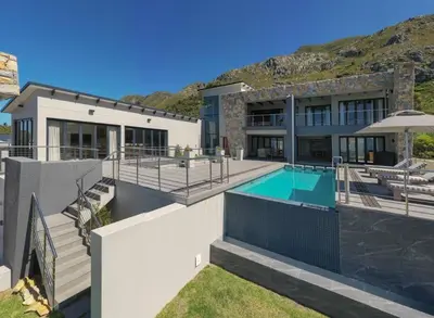 a house with a swimming pool and a mountain at Waterstone Villa in Hermanus