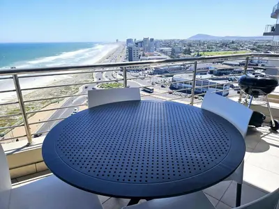 a table on a balcony with a view of the beach at Portico 1103 in Cape Town