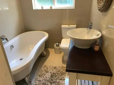 a bathroom with a tub and a sink and a toilet at House in Hermanus Voëlklip in Hermanus