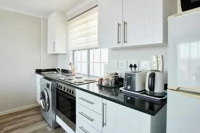a kitchen with white cabinets and a black counter top at The Rondebosch Views in Cape Town