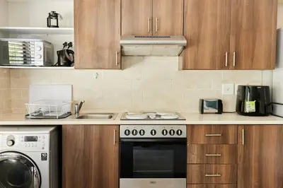a kitchen with wooden cabinets and a stove top oven at The Rondebosch Easy Living in Cape Town