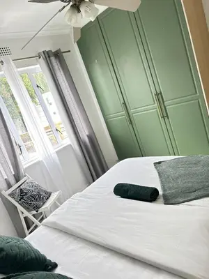 a bedroom with a white bed with a green wall at BREATHE On SOUTH in Cape Town