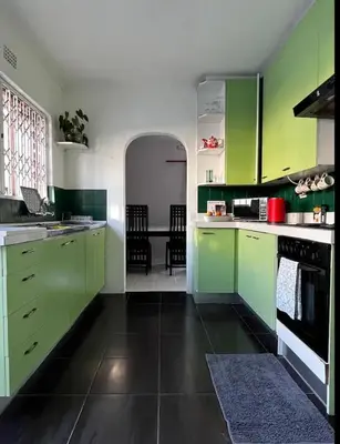 a kitchen with green cabinets and a black floor at BREATHE On SOUTH in Cape Town