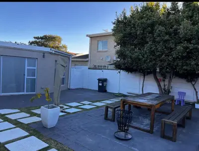 a patio with a wooden table and a tree at BREATHE On SOUTH in Cape Town