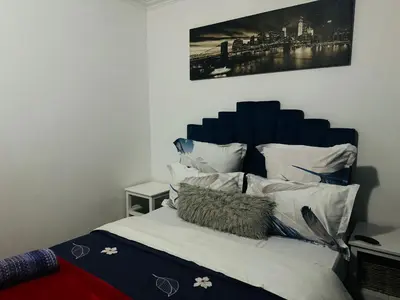 a bedroom with a bed with a blue headboard and pillows at Affordable Guest house in Mwobray in Cape Town