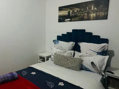 a bed with a blue headboard and white pillows at Affordable Guest house in Mwobray in Cape Town
