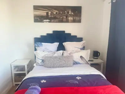 a bed with a blue headboard in a bedroom at Affordable Guest house in Mwobray in Cape Town