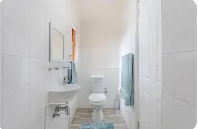 a white bathroom with a toilet and a sink at Lux Suite for 2 - Sunset Beach in Cape Town