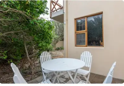 a white table and chairs in front of a house at Lux Suite for 2 - Sunset Beach in Cape Town