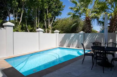 a swimming pool with a fence and a table and chairs at House Simon in Somerset West