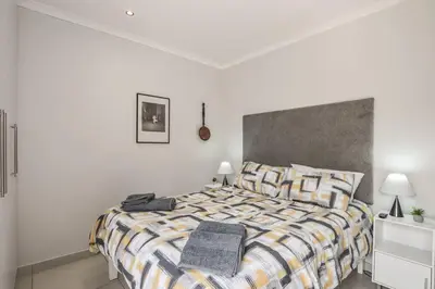 a bedroom with a bed with a striped comforter at WiFi & Solar at Studio on Morgenster in Cape Town