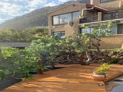 a house with a wooden deck in front of it at Artists Cottages Gordon's Bay in Cape Town